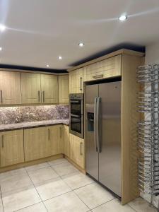 a kitchen with wooden cabinets and a stainless steel refrigerator at Plus Properties Leeds 2 in Bradford