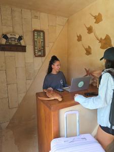 Zwei Frauen sitzen mit einem Laptop an einem Tresen in der Unterkunft Hippie Fish Hostal in Holbox