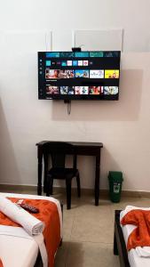 ein Zimmer mit einem Schreibtisch und einem Fernseher an der Wand in der Unterkunft Hotel Marios in Espinal