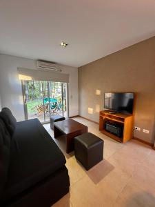 a living room with a couch and a flat screen tv at Complejo Totoras in Pinamar