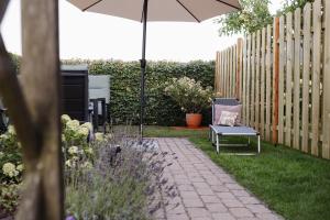 eine Terrasse mit Stuhl und Sonnenschirm im Garten in der Unterkunft Schöne Lage in Lage