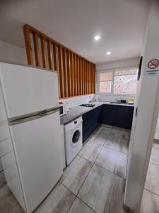 a kitchen with a white refrigerator and a dishwasher at Aires de la costa Renovado in Neuquén