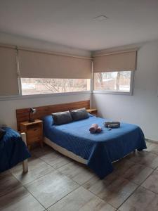 a bedroom with a blue bed and two windows at Aires de la costa Renovado in Neuquén