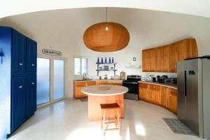 a kitchen with wooden cabinets and a table and a refrigerator at Casa Sofia 19 Guests, Steps From The Sea in Tela