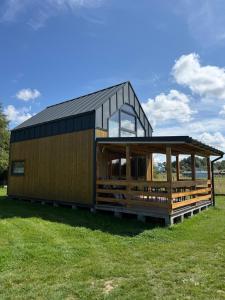 a house with a black roof on a green field at Hortensja in Rusinowo