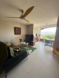 a living room with a couch and a ceiling fan at Flamingo Bay in Les Trois-Îlets