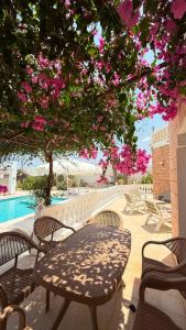 a table and chairs under a tree with pink flowers at La villa jasmin in Al Maqārisah