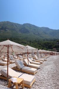 a bunch of lounge chairs and umbrellas on a beach at Apartmani Sutomore Tri Palme in Sutomore