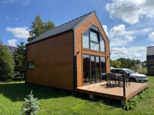 a tiny house with a deck and a table at Hortensja 2 in Rusinowo