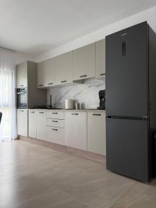 a kitchen with white cabinets and a black refrigerator at Austrian Villa's in Covasna