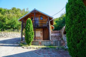 a small house with a wooden door and a tree at Etno Resort Lipa 