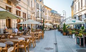 an empty street with tables and chairs and umbrellas at Sergio City Apartments in Craiova