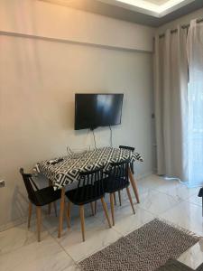 a dining room table with chairs and a flat screen tv at Greysuites in Kavála