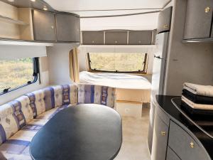 Innenansicht eines Wohnmobils mit Tisch und Bett in der Unterkunft Quinta Lima in Sertã