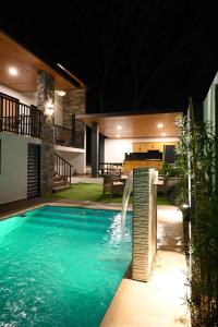 a swimming pool in front of a house at night at villa serenity in Jarabacoa