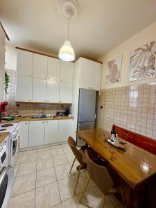 a kitchen with white cabinets and a wooden table at Oasis Pool Flat-near 2 metro stations- in Piraeus