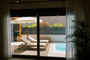 a view of a patio with a pool and an umbrella at Odysseas Seaside Escape by Philoxenia in Artemida