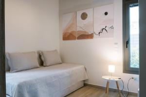 a white bedroom with a bed and a table at Odysseas Seaside Escape by Philoxenia in Artemida +23 photos