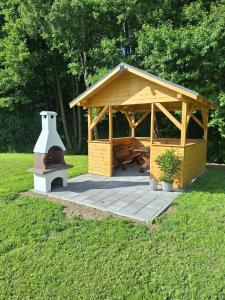 a wooden gazebo with a grill in a park at Apartamenty W Zaciszu in Kamienica Królewska