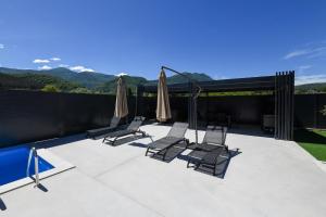 a group of chairs and umbrellas on a patio at Luxury Villa with a Private Pool in Hadžići