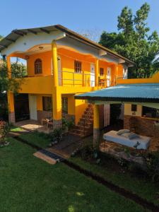 a large yellow house with a porch and a yard at Los Tecales Hostal in Santa Catalina