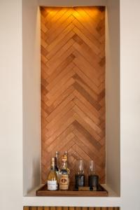 a shelf with bottles and glasses on it with a wooden wall at The Tryst Puerto Vallarta LGBT Hotel in Puerto Vallarta