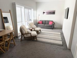 a living room with a couch and chairs and a table at Ohope Coastal Escape in Ohope Beach