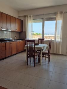 a kitchen with a table and chairs and a kitchen with a window at Kohil Guest House in Ksamil