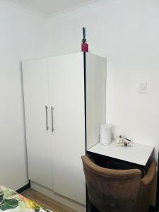 a kitchen with white cabinets and a table and a chair at Alwaba guest house in Mthatha +23 photos