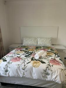 a bed with a floral bedspread and two towels on it at Alwaba guest house in Mthatha