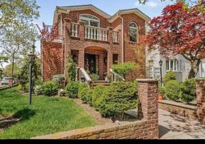 Ein Backsteinhaus mit einem Backsteinzaun im Hof in der Unterkunft Nyc condo in Oakland Gardens