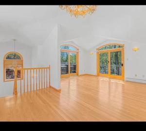ein leeres Wohnzimmer mit Holzboden und Fenstern in der Unterkunft Nyc condo in Oakland Gardens