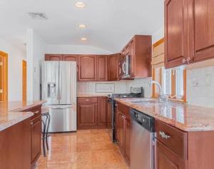 Eine Küche mit Holzschränken und Edelstahlgeräten in der Unterkunft Nyc condo in Oakland Gardens