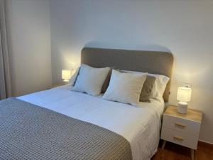 a bed with white pillows and two night stands with lamps at Alma de Lemos - Apartamento Ribeira Sacra in Monforte de Lemos