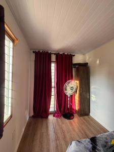 a room with red curtains and a fan in front of a window at My Ideal in Balneario Argentino