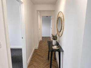 a hallway with a table and a mirror on a wall at Modern Parking Nearby Stores in Swinton