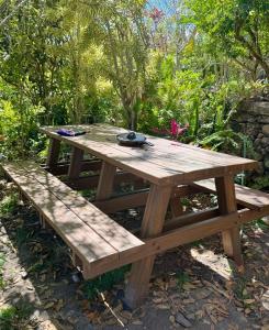 a wooden picnic table and bench in a garden at JAGATÁ- Nossa comunidade in Igatu