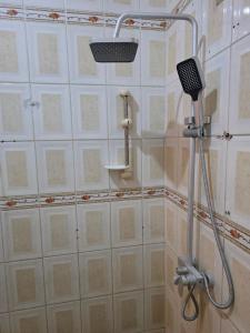 a shower in a bathroom with white tiled walls at Samana hotel ukonga in Dar es Salaam