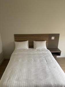 a large white bed with two pillows on it at hote lw des cantons in Weedon-Centre