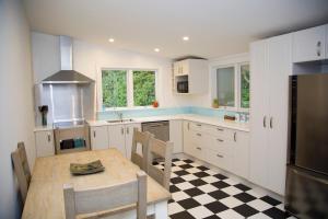 a kitchen with a table and a kitchen with a checkered floor at Cath's cottage in Diamond Harbour