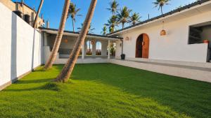 a yard with palm trees and a house at Curve Ahangama in Ahangama