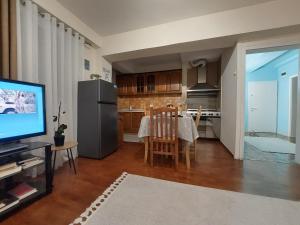 a living room with a kitchen with a table and a television at Solaris Guest House in Shkodër