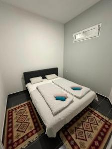 a bedroom with a bed with two pillows and two rugs at Halal Una Royal in Ivišovo Greblje