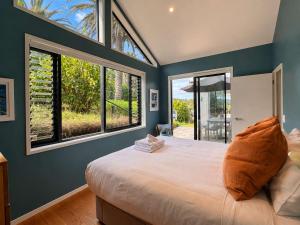 a bedroom with a large bed with blue walls and windows at Art Lovers Retreat - Stay Waiheke in Onetangi +17 photos