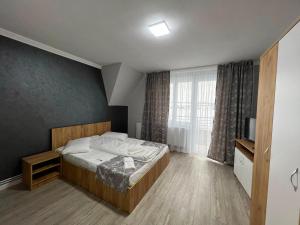 a bedroom with a bed and a large window at Achim-House in Beiuş