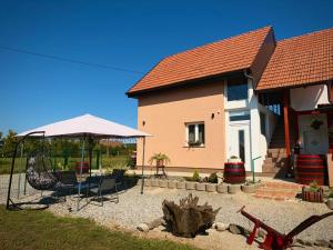 a house with a table and chairs and an umbrella at Kuća za odmor-Zeleni raj in Srpska Kapela