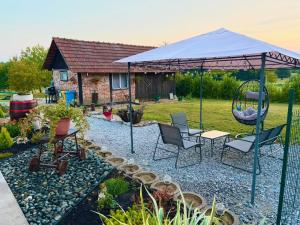 a patio umbrella with chairs and a swing in a yard at Kuća za odmor-Zeleni raj in Srpska Kapela