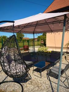 a swing and two chairs under an umbrella at Kuća za odmor-Zeleni raj in Srpska Kapela +29 photos