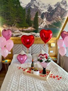 a bed with heart balloons and a table with a bottle of wine at Tatra Widok in Bukowina Tatrzańska