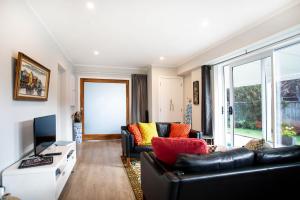 a living room with a black leather couch and a television at Waikanae Beach Suite Retreat in Waikanae